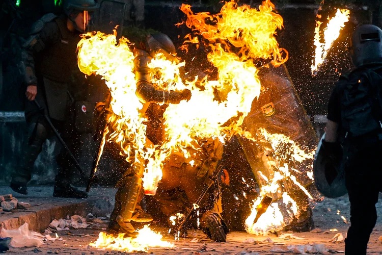 Los carabineros envueltos en llamas en Santiago (AFP)